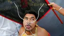 Seorang pemuja dari Kuil Samkong menusukkan besi pada lidahnya dalam Festival Vegetarian di Phuket, Thailand, Selasa (4/10). (REUTERS/Jorge Silva)