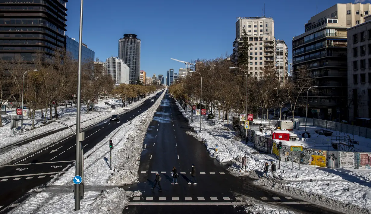 Orang-orang berjalan di sepanjang Paseo Castellana yang tertutup salju di Madrid, Spanyol, Senin (11/1/2021). Ibu kota Spanyol berusaha bangkit kembali setelah menghadapi badai salju terburuk dalam 50 tahun terakhir yang melumpuhkan sebagian besar wilayah Spanyol tengah. (AP Photo/Manu Fernandez)