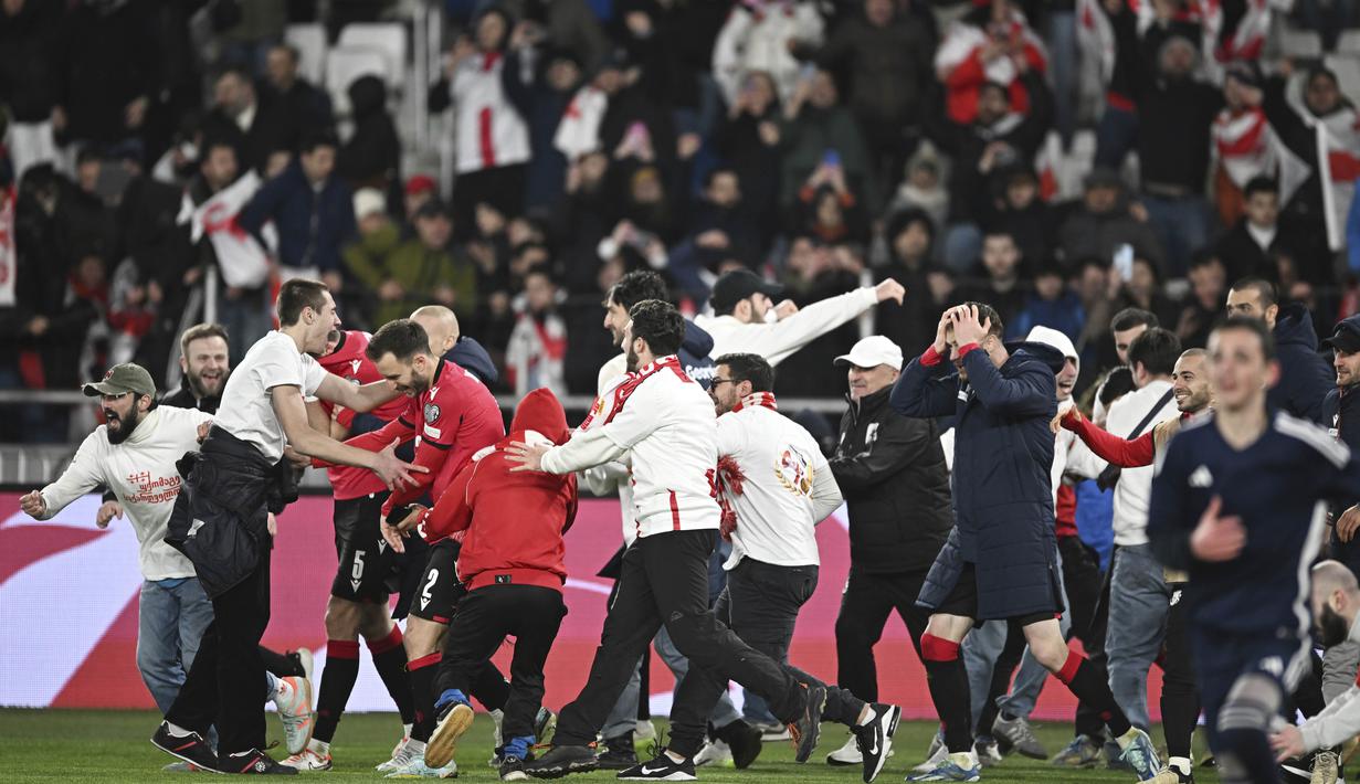 Suporter Timnas Georgia tumpah ruah turun kelapangan setelah timnya berhasil mengalahkan Yunani dalam laga playoff yang menegangkan di Tbilisi, Rabu (27/4/2024). Georgia sukses mencetak sejarah dengan lolos ke Euro 2024 untuk pertama kalinya. (AP Photo/Tamuna Kulumbegashvili)