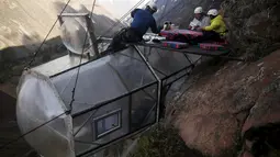 Pemandu menyajikan sarapan kepada tamu di atas kapsul tidur di Skylodge Adventure Suites di Lembah Suci di Cuzco, Peru, 14 Agustus 2015. Hotel  tergantung dengan ketinggian 400 meter ini memiliki tarif sekitar Rp 4 juta per malam. (REUTERS/Pilar Olivares)