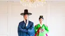Di foto yang lain, Shim Hyung Tak dan Hirai Saya mengenakan baju adat Korea, yaitu hanbok. Hanbok yang dikenakan Shim Hyung Tak berwarna biru jeans, lengkap dengan topi hitamnya bak pangeran di zaman Joseon, sedangkan Hirai Saya mengenakan hanbok berwarna cerah, yaitu hijau dan merah keunguan, riasan wajah bold, dan gaya rambut, serta aksesori bak pengantin zaman dulu. [Foto: Instagram/tak9988]