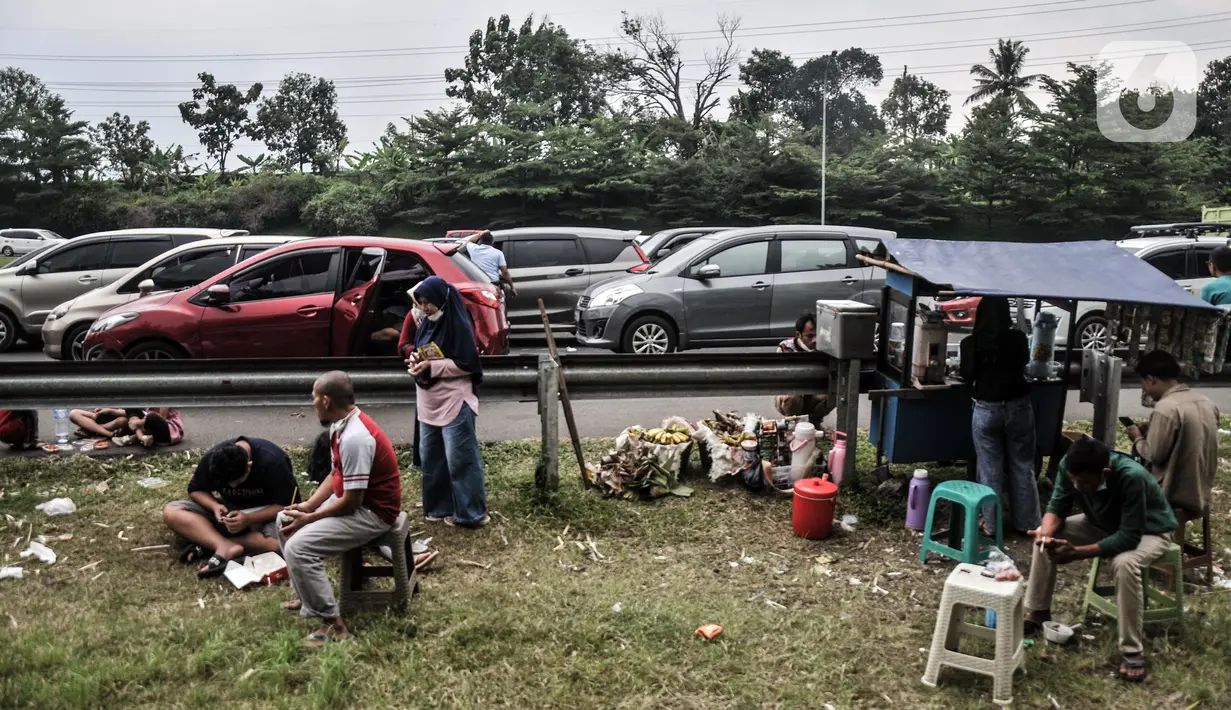 Pedagang berjualan di area penutupan jalur Puncak akibat sistem satu arah di Tol Jagorawi, Pandansari, Bogor, Jawa Barat, Minggu (19/9/2021). Lamanya penutupan memaksa wisatawan turun dari mobil dan beristirahat di pinggir jalan tol. (merdeka.com/Iqbal S. Nugroho)