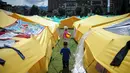 Anak-anak berjalan di dekat tenda di  sebuah kamp yang dibangun untuk para migran Venezuela yang tunawisma di Bogota, Kolombia (21/11). Kamp ini dapat menampung lebih dari 400 orang. (AP Photo/Ivan Valencia)