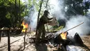 Seorang perwira pasukan keamanan SENAD Paraguay menuangkan dari karung ganja yang dipanen ke dalam api sebagai bagian dari operasi yang diciptakan Aliansi Baru XXXII di Koloni Maria Auxiliadora departemen Amambay di Paraguay utara (24/5/2022). (AP Photo/Jorge Saenz)