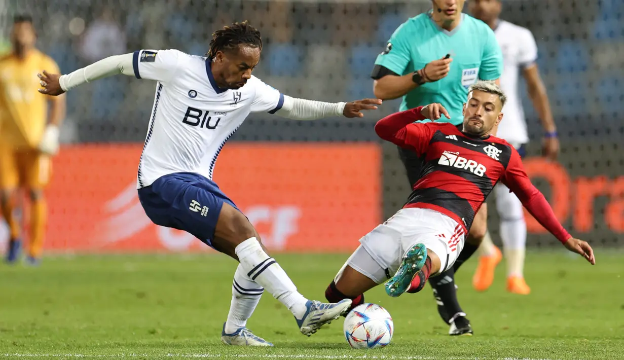 Gelandang Al Hilal, Andre Carrillo berebut bola dengan gelandang Flamengo Giorgian De Arrascaeta dalam duel babak semifinal Piala Dunia Antarklub 2022 di Ibn Batouta Stadium, Rabu (8/2/2023) dini hari WIB. Kali ini tiga gol Al Hilal datang dari dua penalti Salem Al Dawsari (4', 45+9') dan aksi Luciano Vietto (70'). (Fadel SENNA / AFP)