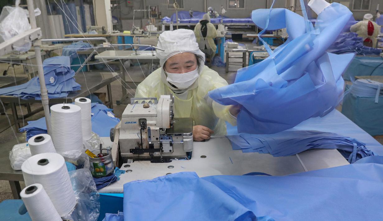 Pekerja memproduksi pakaian pelindung di sebuah pabrik di Nantong, Provinsi Jiangsu, China, Senin (27/1/2020). Pakaian pelindung tersebut diproduksi untuk mendukung pasokan bahan medis saat wabah virus corona melanda China. (STR/AFP)