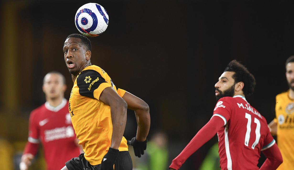 Bek Wolverhampton Wanderers, Willy Boly (kiri) menyundul bola dari ancaman gelandang Liverpool, Mohamed Salah dalam laga lanjutan Liga Inggris 2020/2021 pekan ke-28 di Molineux Stadium, Senin (15/3/2021). Wolverhampton kalah 0-1 dari Liverpool. (AP/Paul Ellis/Pool)