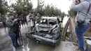 Sejumlah awak media mengambil gambar mobil yang hancur akibat ledakan bom bunuh diri di Kabul, Afghanistan (15/11). Akibat bom bunuh diri ini sedikitnya sembilan orang tewas dan sebagian lainnya mengalami luka-luka. (AP Photo/Rahmat Gul)