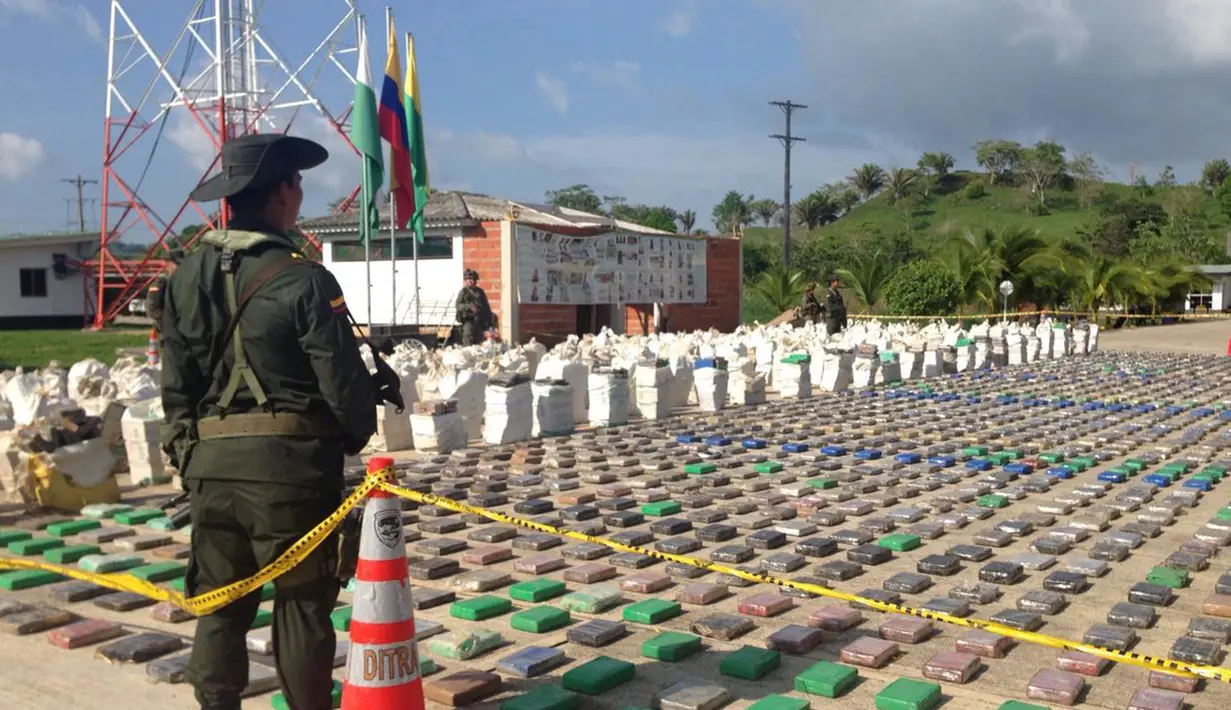 Petugas kepolisian Kolombia menjaga 8 ton paket kokain senilai Rp3,2 triliun yang disita dari sebuah tempat di wilayah Turbo, Antioquia, Minggu (15/5). Selain menyita narkoba, dalam operasi itu polisi juga menangkap 3 orang. (Colombian Police/REUTERS)