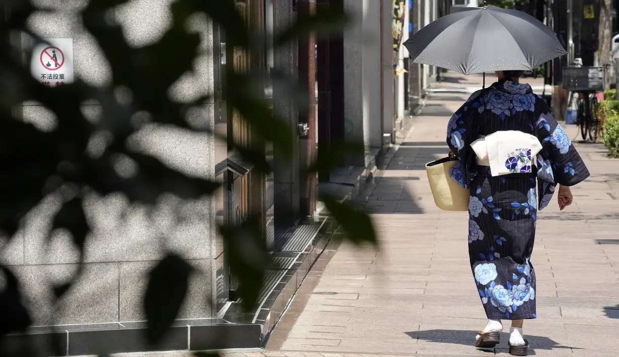 Seorang wanita mengenakan kimono berjalan di bawah terik matahari di Tokyo, Selasa (10/8/2021). Menurut biro meteorologi Jepang, cuaca panas panas terus berlanjut di wilayah metropolitan saat suhu naik menjadi 38 derajat Celcius (100,4 derajat Fahrenheit). (AP Photo/Eugene Hoshiko)