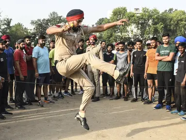 Polisi Punjab melompat saat membimbing pemuda selama pelatihan untuk menjadi Polisi Punjab, di Amritsar (28/6/2021). Polisi Punjab memiliki beragam layanan khusus, termasuk pencegahan dan pendeteksian kejahatan, pemeliharaan hukum dan ketertiban, serta penegakan Konstitusi India. (AFP/Narider Nanu)