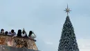 Orang-orang mengambil foto pohon Natal raksasa selama Natal di distrik budaya West Kowloon di Hong Kong (25/12/2021). Pohon Natal raksasa didekorasi secara glamor dengan karangan bunga dan ornamen, berkilauan dengan lampu meriah yang cerah. (AFP/Bertha Wang)