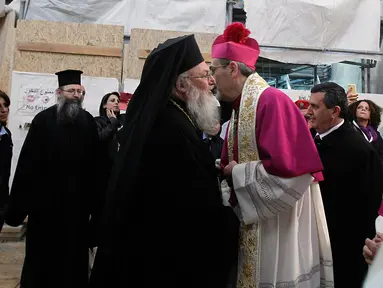 Uskup Agung Ortodoks Yunani Theophylactos (kiri) berpelukan degan Wakil Patriarkal Betlehem Uskup Agung Pierbattista Pizzaballa saat penyambutan di Manger Square di luar Gereja Nativity di Kota Betlehem, Palestina, Minggu (24/12). (AFP/Musa Al Shaer)