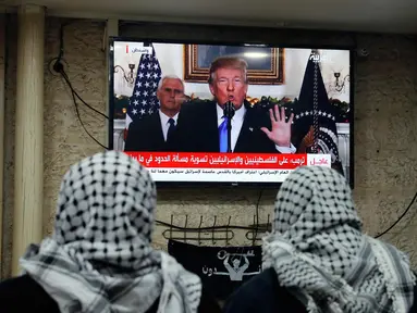 Dua pria Palestina menonton pidato Presiden AS, Donald Trump di sebuah kafe di Yerusalem (6/12). Donald Trump secara resmi mengumumkan bahwa AS mengakui Yerusalem sebagai ibu kota Israel. (AFP Photo/Ahmad Gharabli)
