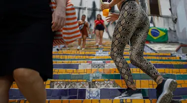Orang-orang berlalu-lalang di anak tangga yang terkenal dengan nama Selaron Steps atau Escadaria Selarón di Rio de Janeiro, Brasil pada 9 Desember 2019. Escadaria Selaron merupakan 250 anak tangga sepanjang 125 meter dengan dua ribuan ubin berwarna-warni. (Photo by David GANNON / AFP)