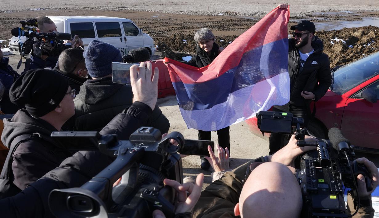 Penggemar dengan bendera nasional Serbia menunggu kedatangan Novak Djokovic di depan terminal VIP di bandara Nikola Tesla di Belgrade, Senin (17/1/2022). Novak Djokovic diperkirakan akan tiba di ibu kota Serbia setelah dideportasi dari Australia terkait status vaksinasinya (AP Photo/Darko Vojinovic)