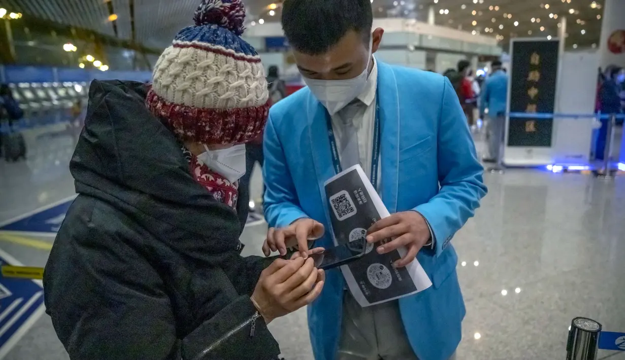 Pekerja membantu pelancong mengisi status kesehatan elektronik COVID-19 mereka di area kedatangan internasional di Bandara Internasional Beijing, China (9/1/2023). Pelancong internasional pertama tiba di China tanpa karantina wajib yang telah diberlakukan pada awal penerbangan. Pandemi tiga tahun lalu setelah pembatasan dicabut mulai hari Minggu. (AP/Mark Schiefelbein)