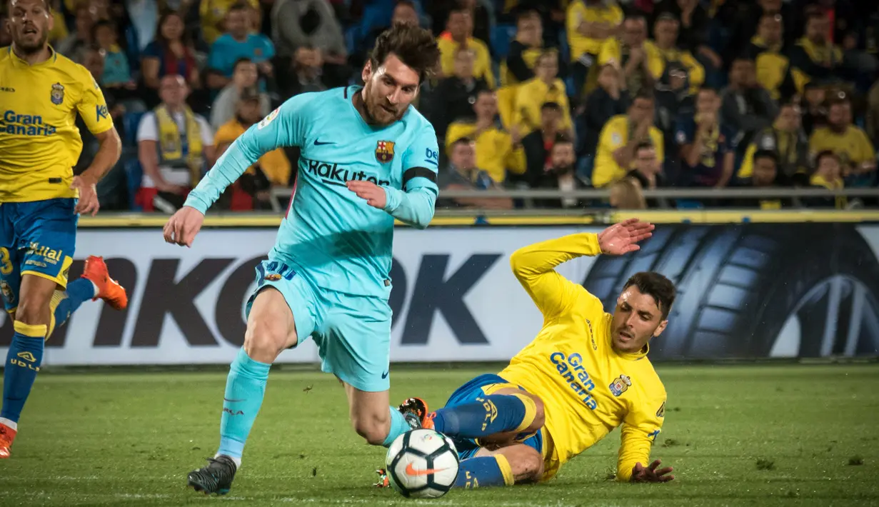 Pemain Barcelona Lionel Messi berebut bola dengan bek Las Palmas, Ximo Navarro Jimenez pada jornada ke-26 La Liga 2017-2018 di Estadio Gran Canaria, Kamis (1/3). Barcelona gagal menang karena tuan rumah menahan imbang dengan skor 1-1. (DESIREE MARTIN/AFP)