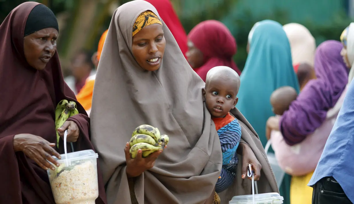 Sejumlah wanita Somalia berjalan sambil membawa iftar (makanan berbuka puasa) dari sebuah organisasi amal Qatar selama bulan suci Ramadan, di ibukota Mogadishu, Senin (22/6/2015). (REUTERS/Feisal Omar)