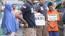 Petugas merangkul Anwar alias Rizal, tersangka  pembunuhan bocah 12 tahun, Adinda Anggia Putri di Rusun Benhil, Jakarta, Minggu (29/11/2015). Anwar melakukan reka ulang pembunuhan yang telah dilakukannya kepada Adinda. (Liputan6.com/Angga Yuniar) 
