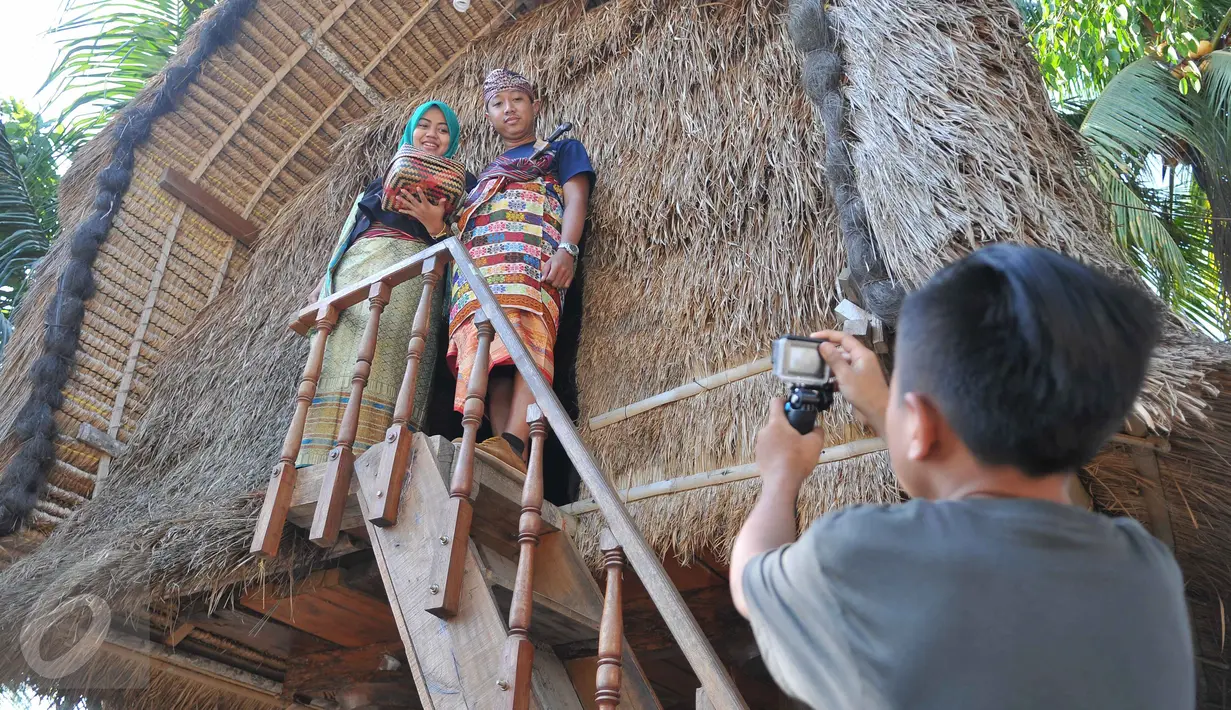 Wisatawan berfoto sambil mengenakan kain tenun songket di sentral kerajinan songket Patuh, Desa Sukarara, Lombok Tengah, Selasa (13/10). Desa Sukarara menjadi salah satu penghasil kain tenun khas suku Sasak, Lombok. (Liputan6.com/Gempur M Surya)