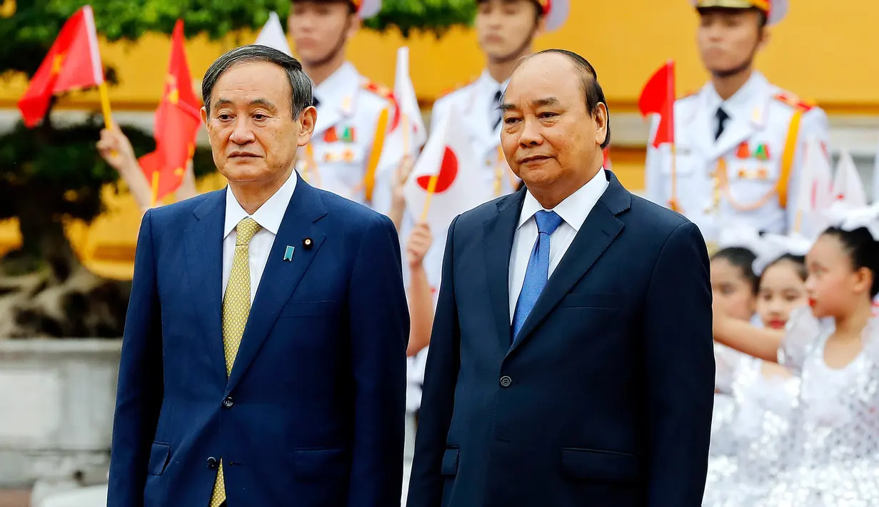 PM Jepang Yoshihide Suga (kiri) berjalan bersama dengan PM Vietnam Nguyen Xuan Phuc meninjau pasukan kehormatan di Istana Kepresidenan, di Hanoi, Vietnam, Senin (19/10/2020). Yoshihide Suga melakukan kunjungan resmi ke Vietnam hingga 20 Oktober 2020. (Kham/Pool Photo via AP)