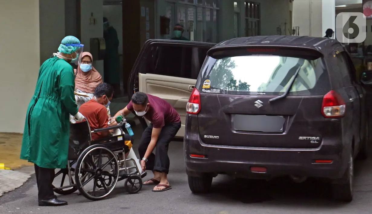 Petugas medis (kiri) mendorong pasien yang duduk di kursi roda di IGD RSUD Cengkareng, Jakarta, Rabu (23/6/2021). Meningkatnya kasus COVID-19 di Jakarta membuat pasien harus mengantre di luar IGD untuk mendapatkan tempat perawatan. (Liputan6.com/Herman Zakharia)