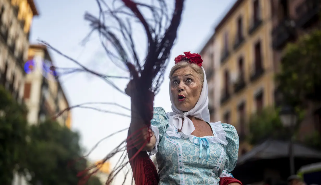 Seorang wanita mengenakan pakaian tradisional daerah Madrid dan dikenal sebagai 'Chulapa' menari selama perayaan San Cayetano, santo pelindung tenaga kerja dan roti, di lingkungan Lavapies di Madrid, Spanyol, Sabtu (6/8/2022). Festival San Cayetano menandai awal dari serangkaian festival populer di Madrid. (AP Photo/Manu Fernandez)