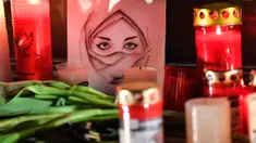 Gambar seorang wanita terlihat di antara lilin dan bunga saat berkabung untuk para korban penembakan brutal di Hanau, Jerman, Kamis (20/2/2020). Penembakan yang terjadi di dua bar shisha Kota Hanau menewaskan sembilan orang dan melukai sejumlah orang lainnya. (AP Photo/Martin Meissner)