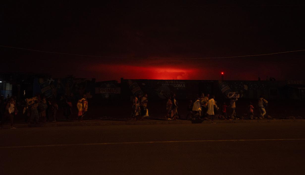 Penduduk meninggalkan kota menyusul aktivitas mendadak gunung berapi Nyiragongo di Goma, Kongo, Sabtu (22/5/2021). Akibat gunung Nyiragongo meletus, listrik pun terputus di sebagian besar kota ketika ratusan penduduk mulai meninggalkan rumah mereka dengan berjalan kaki. (Guerchom Ndebo/AFP)