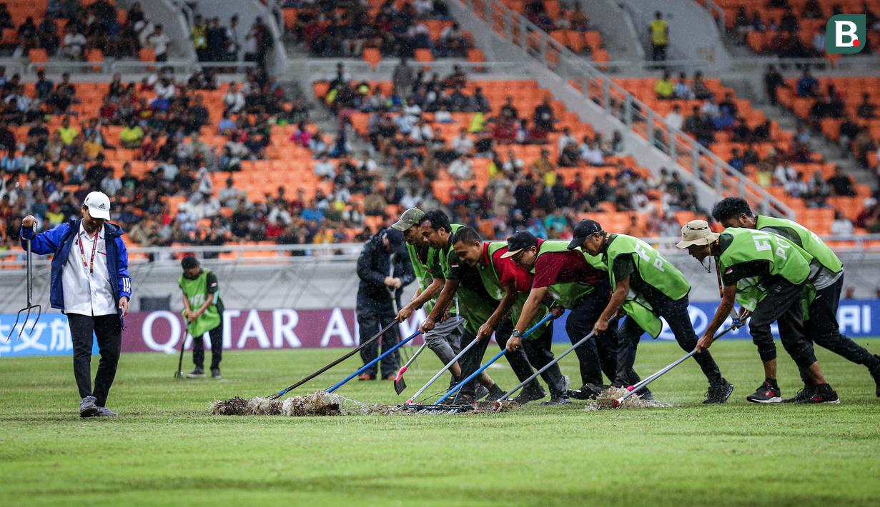 Sejumlah petugas menyingkirkan air yang menggenangi lapangan Jakarta International Stadium (JIS) jelang laga perempat final Piala Dunia U-17 2023 antara Timnas Brasil U-17 melawan Timnas Argentina U-17, Jumat (24/11/2023). (Bola.com/Bagaskara Lazuardi)