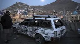 Seorang pria memeriksa kondisi mobil yang rusak usai ledakan bom di Kabul, Afganistan (28/12/2020). Sebanyak 4 orang tewas akibat ledakan yang terjadi di dua tempat terpisah tersebut. (AP Photo/Rahmat Gul)