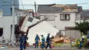 Petugas pemadam dan polisi memeriksa kondisi rumah yang rusak akibat tornado di Koshigaya, pinggiran kota Tokyo. (AFP/Yoshikazu Tsuno/wwn)