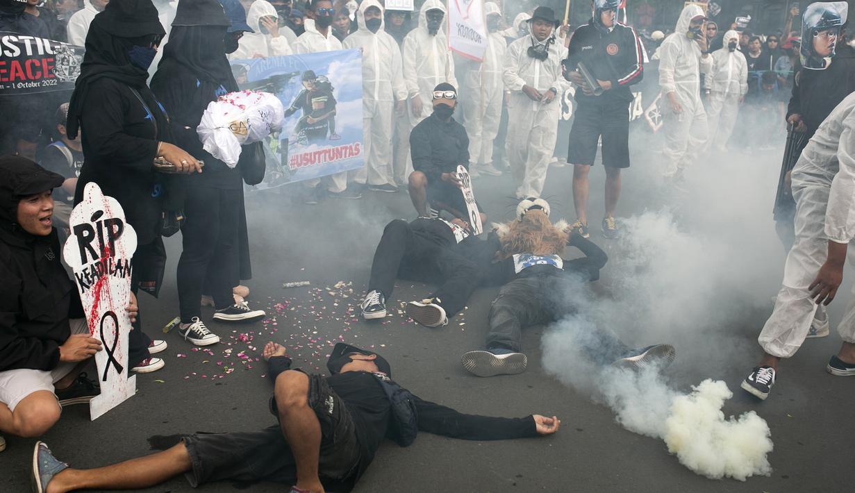 Pengunjuk rasa melakukan teatrikal memperagakan penembakan gas air mata ke tribun penonton saat mengikuti unjuk rasa memperingati 40 hari Tragedi Kanjuruhan, di Malang, Jawa Timur, Kamis (10/11/2022). Gas air mata ini berakibat penonton berdesak-desakan mencari jalan keluar hingga memakan korban jiwa. (AP Photo/Rizki Dwi Putra)