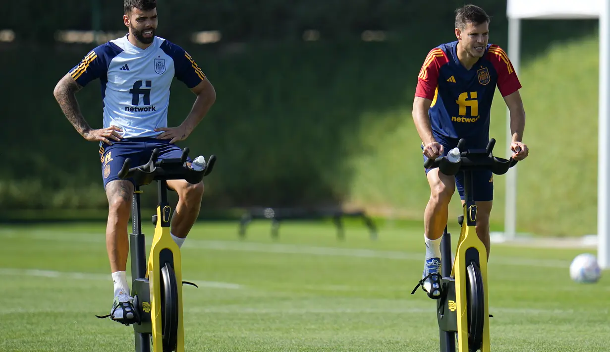 Kiper Spanyol, David Raya (kiri) dan bek Cesar Azpilicueta berlatih sepeda statis saat sesi latihan di Qatar University di Doha, Qatar, Minggu, 4 Desember 2022. Spanyol lolos ke babak 16 besar dengan status runner-up Grup E dengan torehan empat poin. (AP Photo/Julio Cortez)