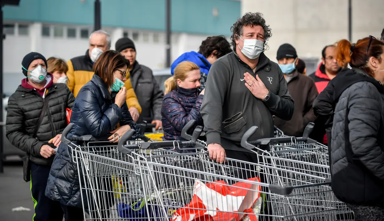 Orang-orang mengenakan masker antre di luar sebuah supermarket di Casalpusterlengo, Minggu (23/2/2020). Mereka memborong perlengkapan dan bahan-bahan kebutuhan pokok karena tak mau keluar rumah menyusul dua warga Italia yang meninggal karena Virus Corona COVID-19. (Claudio Furlan/Lapresse via AP)