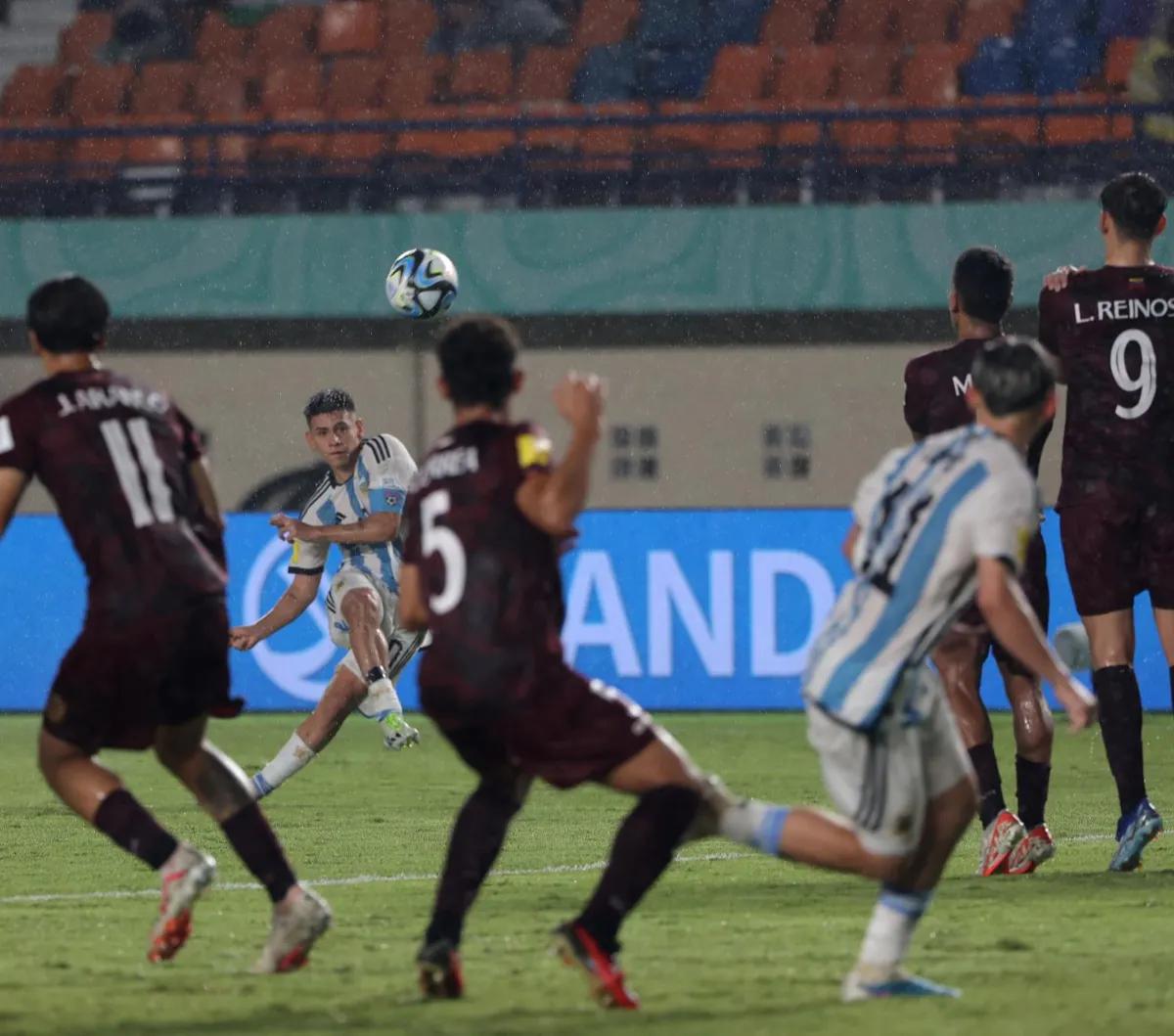 Pemain Timnas Argentina U-17, Claudio Echeverri melakukan eksekusi tendangan bebas ke arah gawang Timnas Venezuela U-17 pada laga 16 besar Piala Dunia U-17 2023. Pertandingan tersebut berlangsung seru dengan intensitas tinggi di Stadion Si Jalak Haroepat