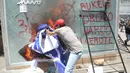 Seorang demonstran merusak ATM Bitcoin bernama Chivo selama protes terhadap kebijakan Presiden Nayib Bukele pada Hari Kemerdekaan di San Salvador, El Salvador, Rabu (15/9/2021). Massa juga memprotes Bukele yang dikhawatirkan kembali mengikuti pemilihan pada tahun 2024 mendatang. (MARVIN RECINOS/AFP)
