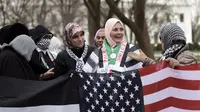 Warga Muslim berkumpul menggelar aksi protes di depan Gedung Putih, Washington DC, AS, Jumat (8/12). Beberapa dari mereka mengenakan syal keffiyeh khas Palestina atau memakai warna-warna yang menyimbolkan bendera Palestina. (Eric BARADAT / AFP)