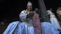 Seorang pendeta Hindu bersiap-siap untuk ambil bagian dalam perayaan pada hari kesepuluh festival Dashain di sebuah kuil di Bhaktapur di pinggiran Kathmandu (15/10/2021). (AFP/Prakash Mathema)