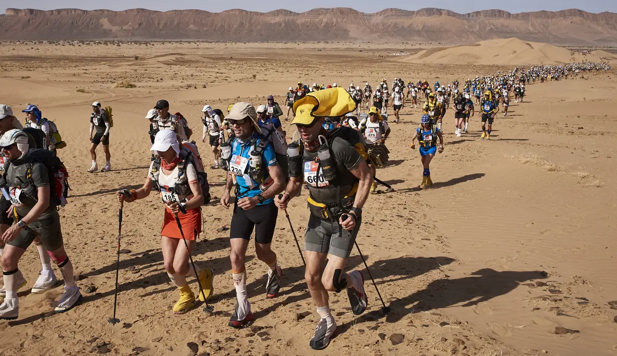 Para peserta bersaing dalam kejuaraan Marathon des Sables ke-32 tahap ketiga di Gurun Sahara, selatan Maroko, Selasa (11/4). Para peserta diwajibkan membawa tas berisikan makanan, perlengkapan tidur dan material lainnya. (JEAN-PHILIPPE KSIAZEK/AFP)