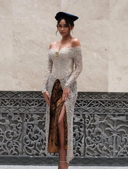 Penampilan stunning top model Indonesia, Sarah Tumiwa yang mengenakan kebaya panjang asimetris dengan aksen off-shoulder warna silver saat wisuda. Ia menambahkan rok batik dengan model slit. [@sarahtumiwa]