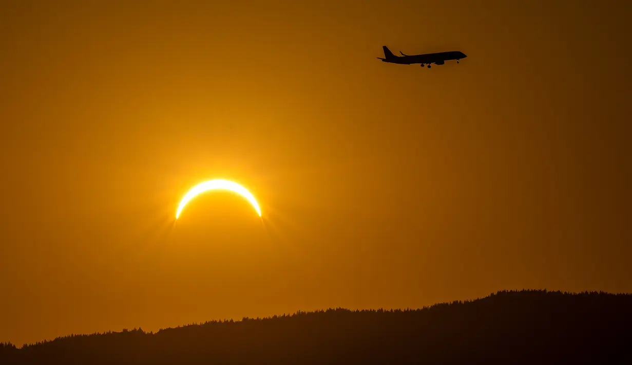 Sebuah pesawat terbang melintas saat gerhana matahari sebagian di Bernex dekat Jenewa, Swiss, Rabu, 12 Agustus 2026. (Martial Trezzini/Keystone via AP)