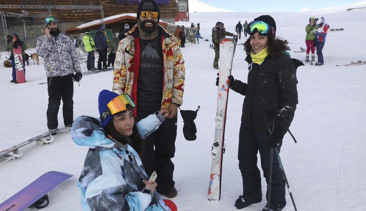 Pemain ski beristirahat di dasar lereng di resor ski Tochal tepat di luar ibu kota Teheran, Iran (1/1/2022). Di tengah polusi udara dan kesengsaraan ekonomi, penduduk Teheran menemukan kenyamanan di resor ski di utara Teheran di pegunungan Alborz. (AP Photo/Vahid Salemi)