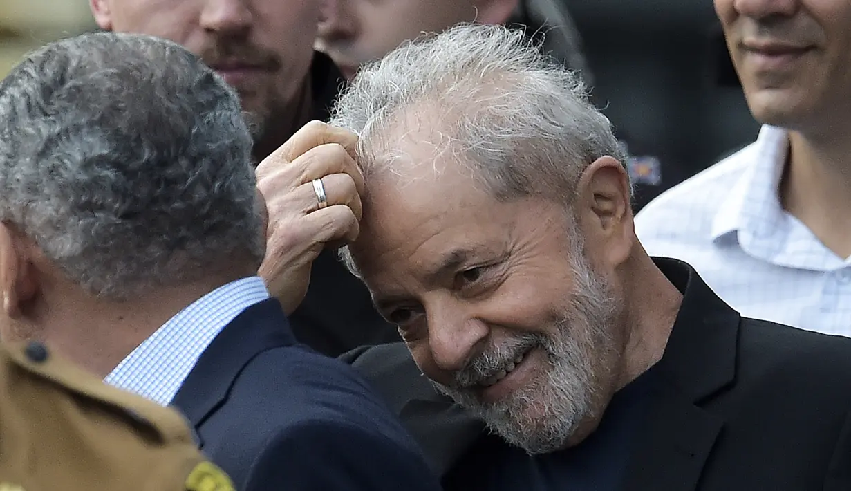 Mantan Presiden Brasil Luiz Inacio Lula da Silva tersenyum sambil mengaruk kepalanya setelah dibebaskan di Curitiba, Brasil, (8/11/2019). Mantan presiden yang kini berusia 74 tahun itu, pemimpin Brasil selama 2003 hingga 2010, dipandang sebagai ikon kiri di negara itu. (AFP Photo/Carl De Souza)