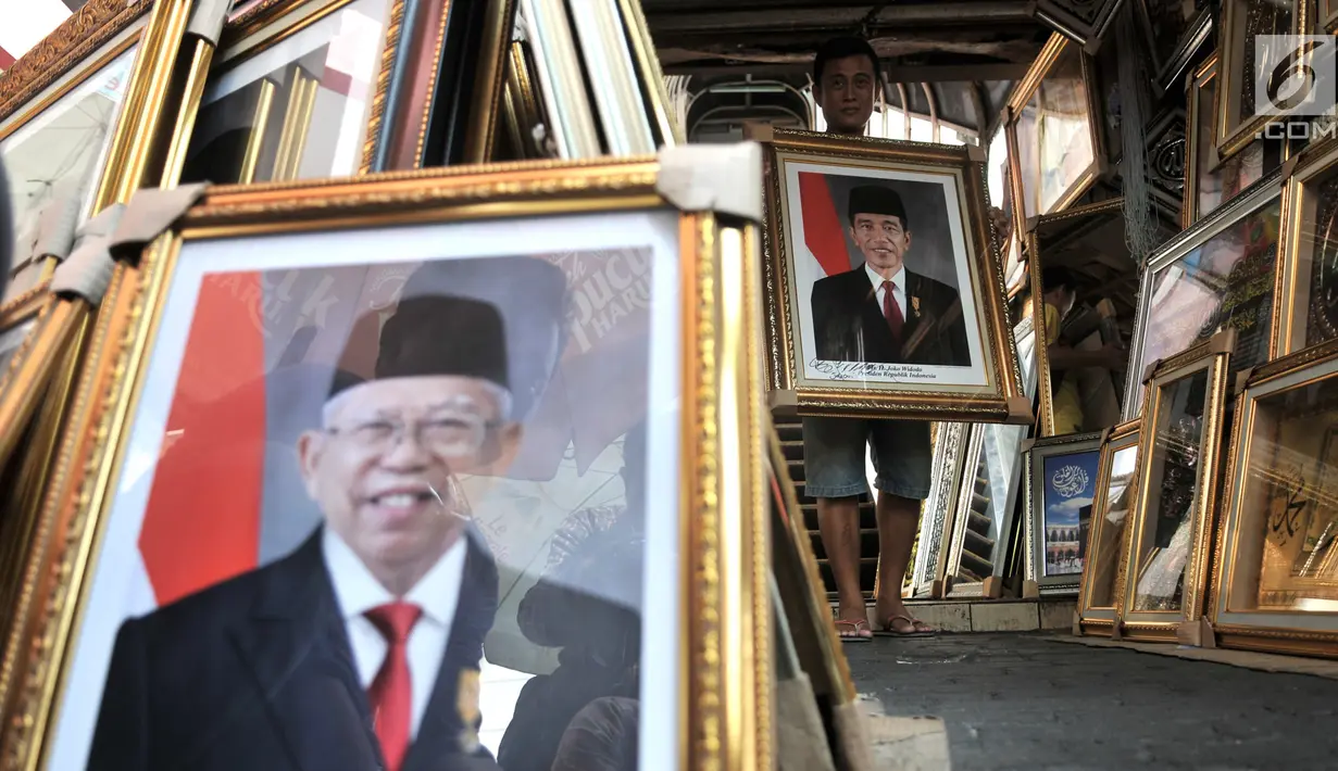 Pedagang merapikan foto Presiden-Wapres 2019-2024, Joko Widodo-KH Ma'ruf Amin di salah satu toko di Pasar Baru, Jakarta, Senin (26/8/2019). Foto Presiden dan Wapres Terpilih dijual Rp 200 ribu hingga Rp 900 ribu per paket (foto presiden dan wakil presiden). (merdeka.com/Iqbal S. Nugroho)
