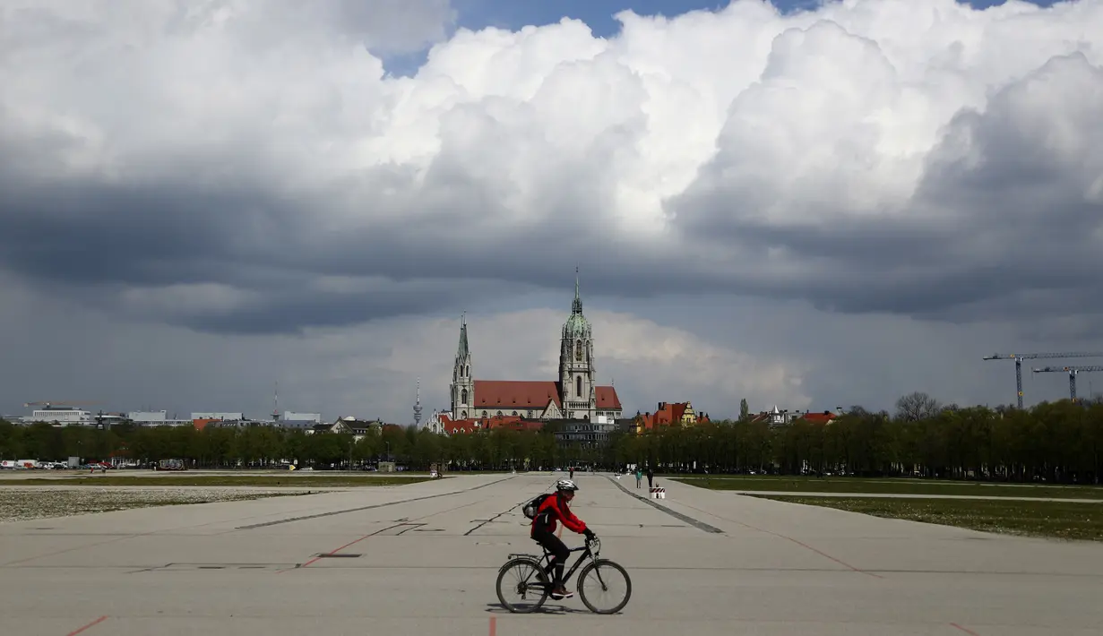 Seorang pengendara sepeda melintasi area Theresienwiese, tempat festival bir 'Oktoberfest' diadakan, di depan gereja St. Pauls di Munich, Senin (3/5/2021). Jerman kembali membatalkan festival bir Oktoberfest untuk tahun kedua karena pandemi covid-19. (AP Photo/Matthias Schrader)