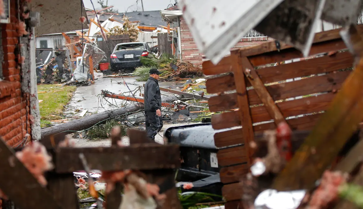Seorang pria berjalan didekat puing-puing rumah yang rusak akibat dihantam Tornado di New Orleans, AS (7/2). Gubernur John Bel Edwards mengumumkan keadaan darurat untuk wilayah Louisiana. (AP Photo/Gerald Herbert)