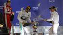 Lewis Hamilton (tengah) menyemprotkan sampanye kea rah peringkat tiga, Nico Rosberg (kanan), dan Kimi Raikkonen dari Ferrari. (photo by AFP/MARWAN NAAMANI)