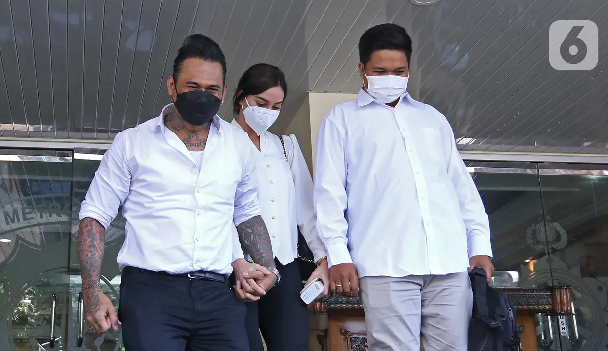 Musikus I Gede Ary Astina alias Jerinx didampingi istrinya, Nora Alexandra (tengah) meninggalkan Polda Metro Jaya, Jakarta, Sabtu (14/8/2021). Polisi memulangkan Jerinx yang sudah menjadi tersangka kasus pengancaman usai bermediasi dengan pengiat sosial Adam Deni. (Liputan6.com/Herman Zakharia)